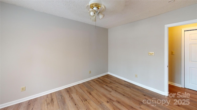 unfurnished room with a textured ceiling, wood finished floors, and baseboards