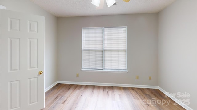 empty room featuring a ceiling fan, a textured ceiling, baseboards, and wood finished floors