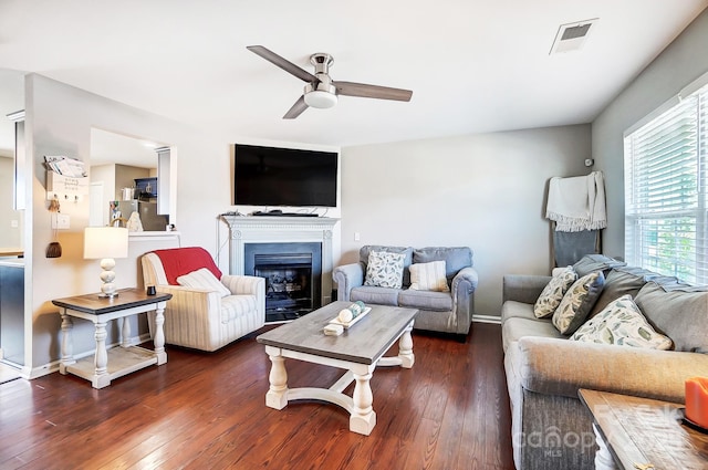 living area featuring visible vents, hardwood / wood-style floors, a ceiling fan, a glass covered fireplace, and baseboards