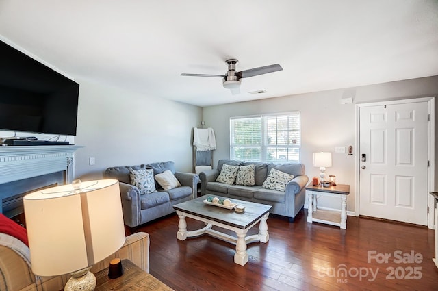 living room with wood-type flooring, a fireplace, visible vents, and a ceiling fan