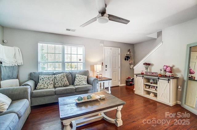 living room featuring dark wood-style floors, visible vents, baseboards, and a ceiling fan