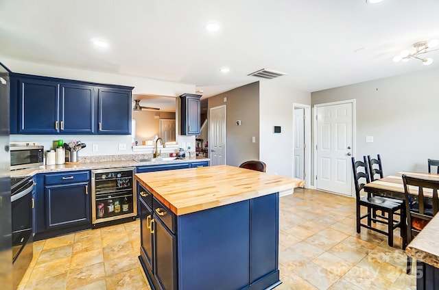 kitchen featuring beverage cooler, a sink, visible vents, wood counters, and stainless steel microwave