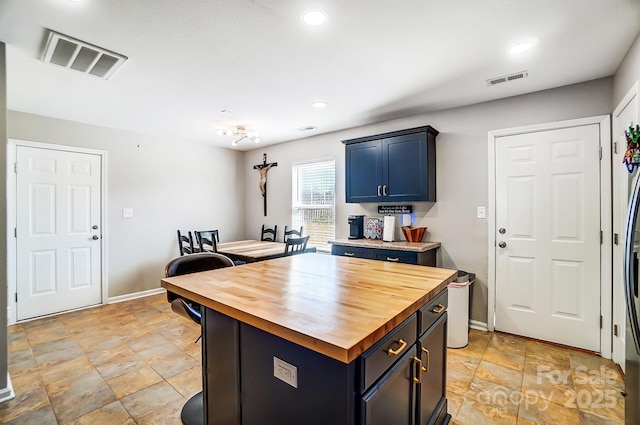 kitchen featuring butcher block countertops, blue cabinetry, visible vents, and recessed lighting