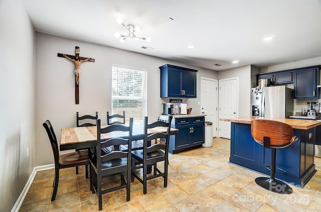 kitchen with blue cabinets, visible vents, wooden counters, a center island, and stainless steel fridge