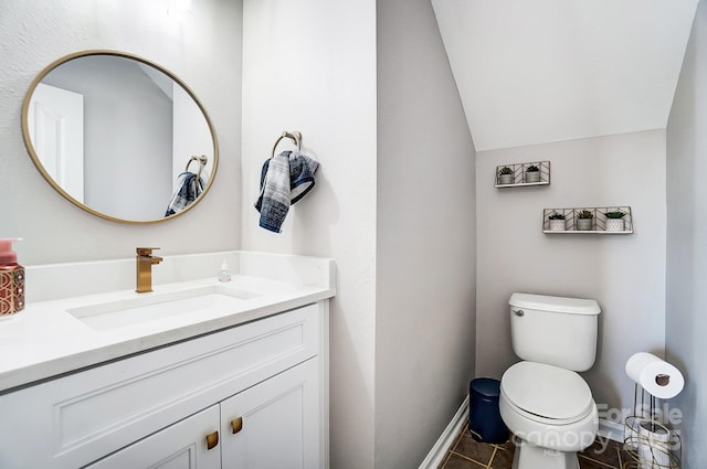 bathroom featuring lofted ceiling, tile patterned flooring, toilet, vanity, and baseboards