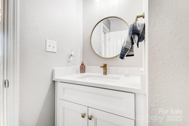 bathroom with a textured wall and vanity