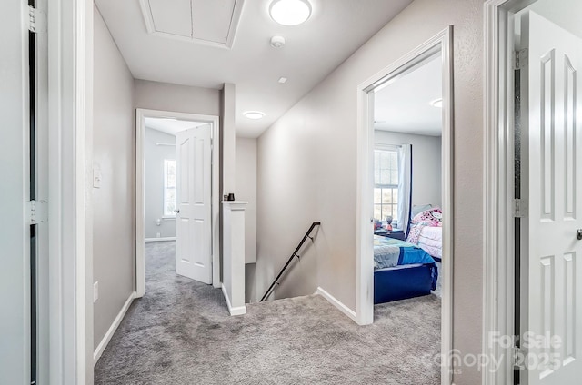 hallway featuring carpet floors, attic access, baseboards, and an upstairs landing