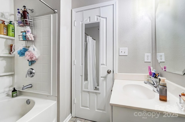 bathroom featuring a textured wall, shower / bathtub combination with curtain, and vanity