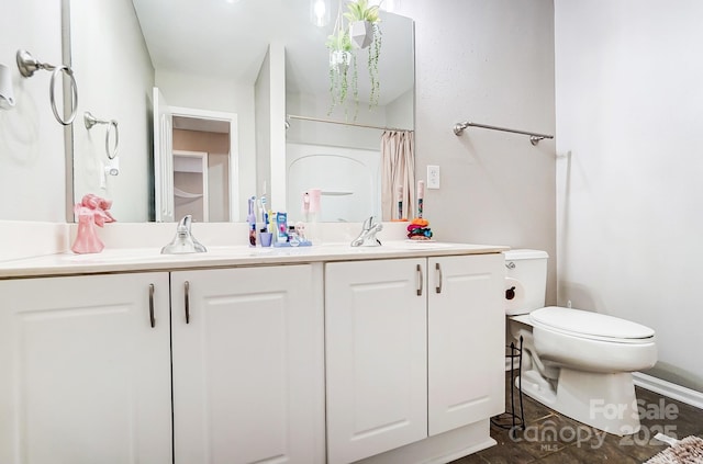 bathroom with toilet, double vanity, and a sink