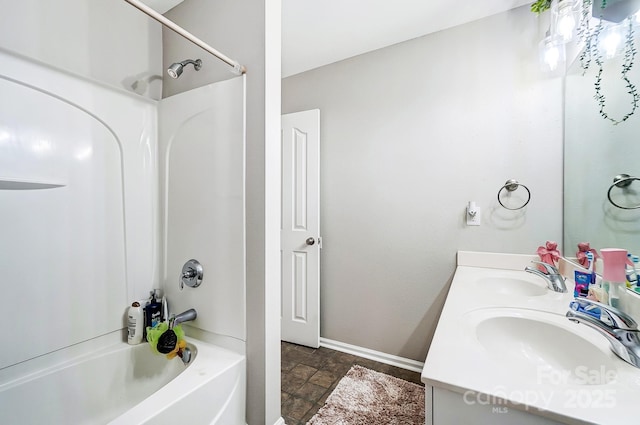 full bath with double vanity, tub / shower combination, a sink, and baseboards