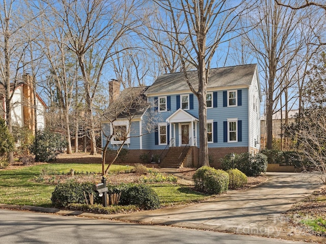 colonial inspired home with brick siding and a chimney