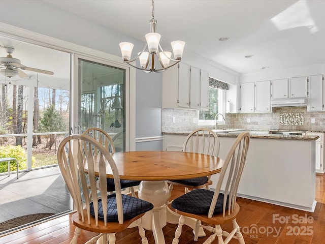 dining area featuring ceiling fan with notable chandelier and wood finished floors