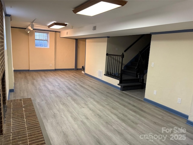 basement featuring visible vents, stairway, and wood finished floors