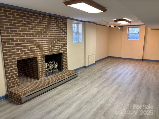 interior space featuring a baseboard heating unit, wood finished floors, a fireplace, and baseboards