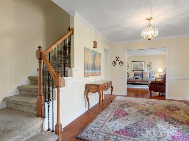 entrance foyer featuring hardwood / wood-style floors, a notable chandelier, stairs, and ornamental molding