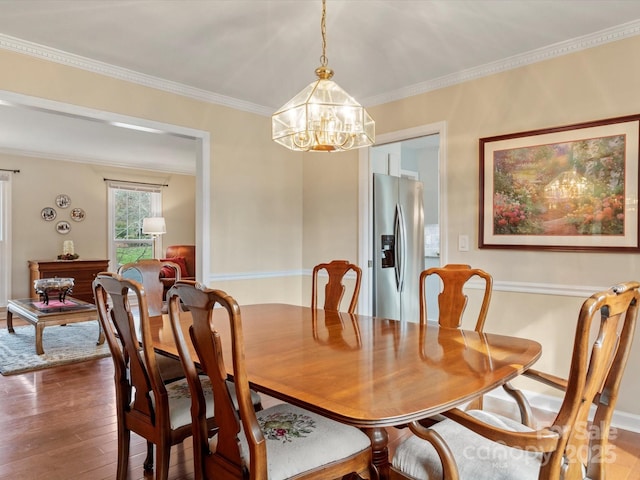 dining space featuring crown molding, wood finished floors, and a chandelier