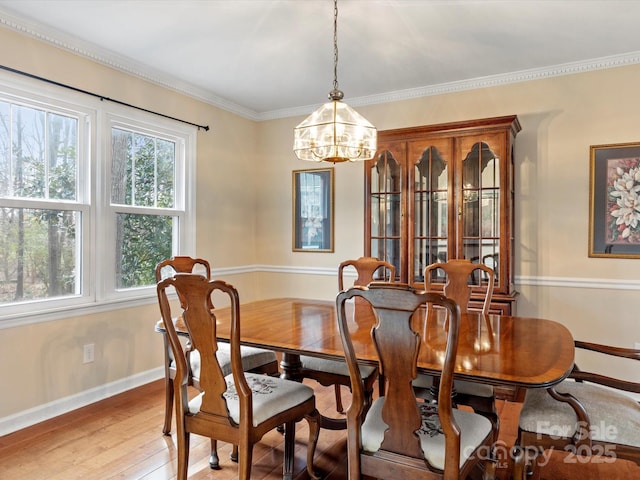 dining space with crown molding, light wood-style floors, baseboards, and a chandelier