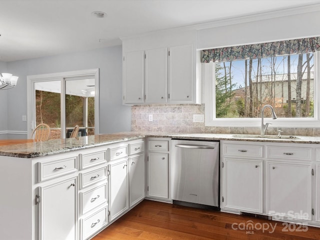 kitchen with light stone counters, a peninsula, stainless steel dishwasher, white cabinetry, and a sink