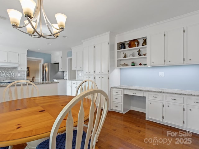 dining room with a chandelier, dark wood finished floors, and built in study area