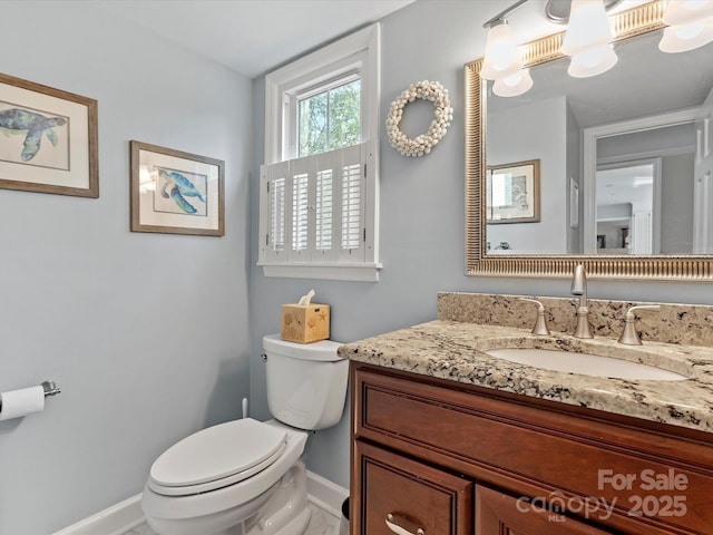 bathroom featuring vanity, toilet, and baseboards