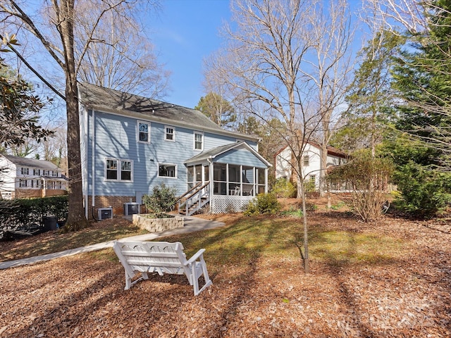 back of property with central AC and a sunroom