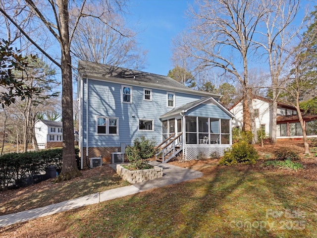 rear view of property with central air condition unit and a sunroom