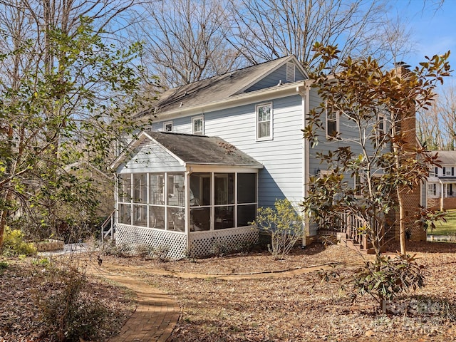 rear view of house with a chimney and a sunroom