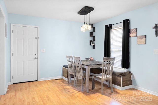 dining room with baseboards, light wood finished floors, and an inviting chandelier