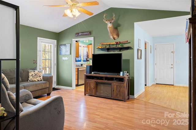 living area with light wood-type flooring, ceiling fan, baseboards, and lofted ceiling