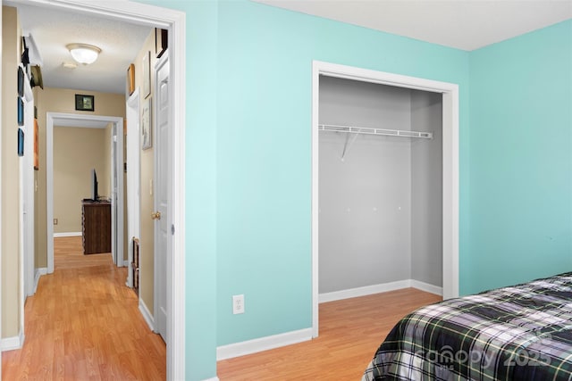 bedroom featuring a closet, light wood-style flooring, and baseboards