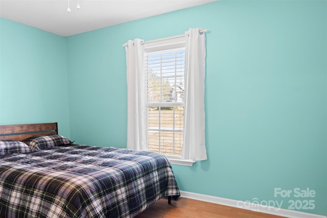 bedroom with multiple windows, baseboards, and wood finished floors