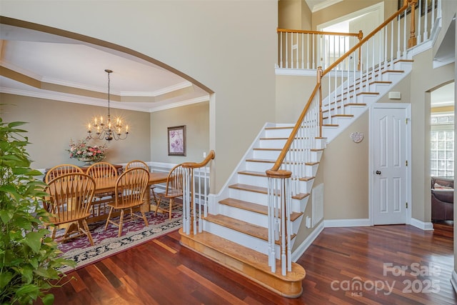 interior space featuring arched walkways, ornamental molding, wood finished floors, a chandelier, and baseboards