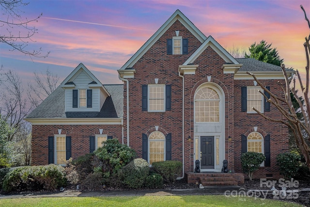 view of front of home featuring brick siding and a shingled roof