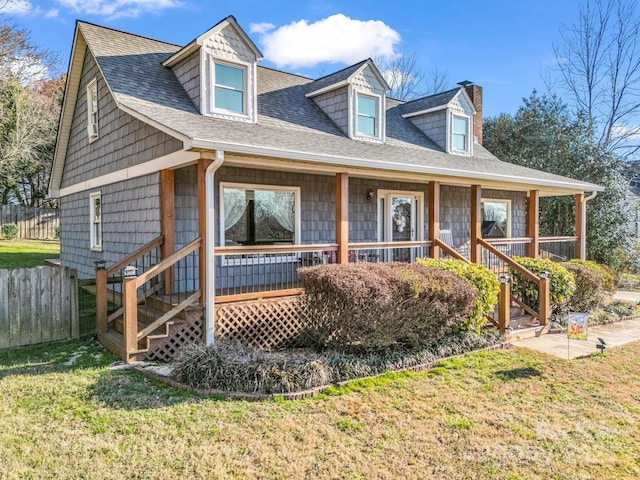 view of front of house with fence, a porch, roof with shingles, a front yard, and a chimney