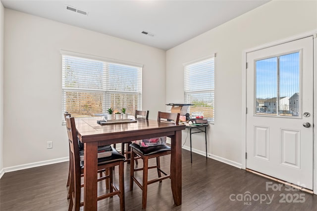 dining space with dark wood-style flooring, visible vents, and baseboards