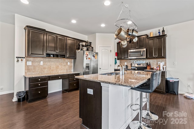 kitchen featuring stainless steel appliances, dark wood-style flooring, a sink, and dark brown cabinets