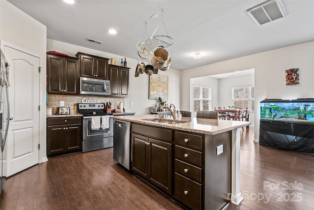 kitchen with dark wood-type flooring, visible vents, stainless steel appliances, and a sink