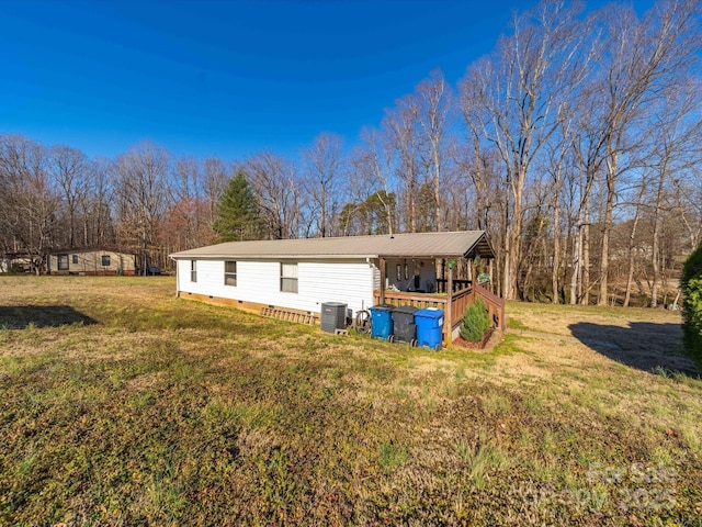 view of side of property with crawl space, central air condition unit, metal roof, and a yard