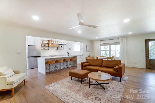 living room with recessed lighting, light wood-style flooring, baseboards, and a ceiling fan