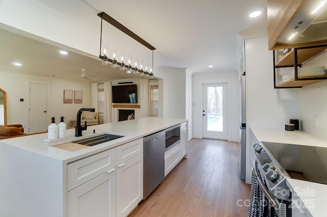 kitchen featuring a sink, decorative light fixtures, open floor plan, white cabinetry, and stainless steel appliances