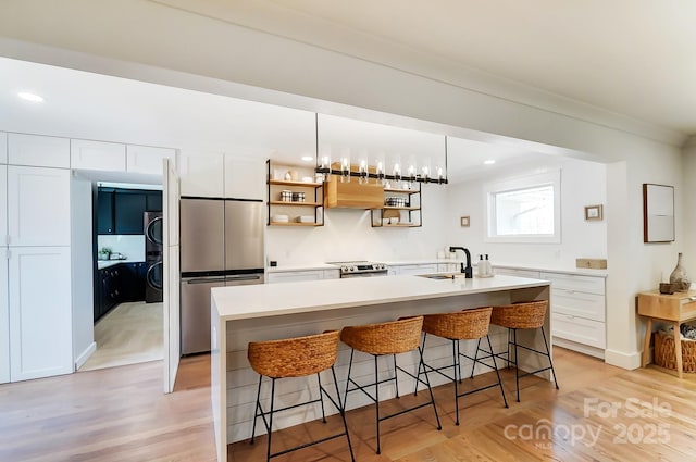 kitchen with a breakfast bar, white cabinets, stainless steel appliances, and a sink