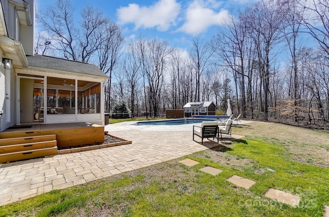 view of yard featuring a fenced in pool, fence, an outdoor structure, a sunroom, and a patio