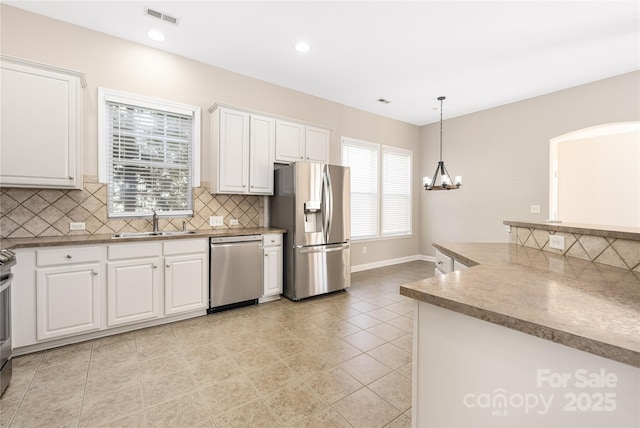 kitchen featuring visible vents, appliances with stainless steel finishes, white cabinetry, a sink, and a chandelier