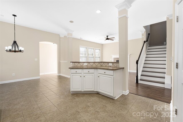 kitchen featuring light tile patterned floors, arched walkways, ceiling fan with notable chandelier, dark countertops, and decorative light fixtures