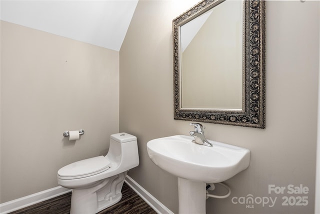 bathroom with lofted ceiling, wood finished floors, toilet, and baseboards