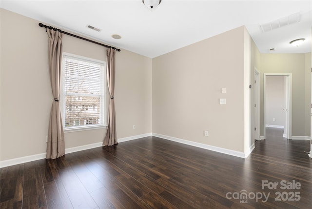 empty room with visible vents, dark wood finished floors, and baseboards