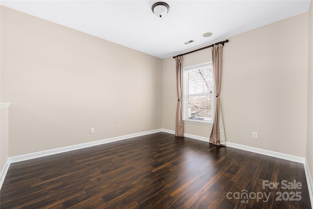 unfurnished room featuring dark wood finished floors, visible vents, and baseboards