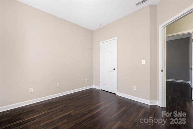 empty room featuring baseboards, visible vents, and dark wood finished floors