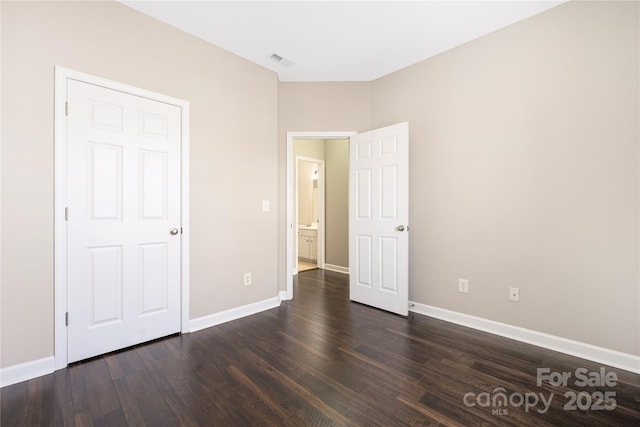 unfurnished bedroom featuring visible vents, dark wood finished floors, and baseboards