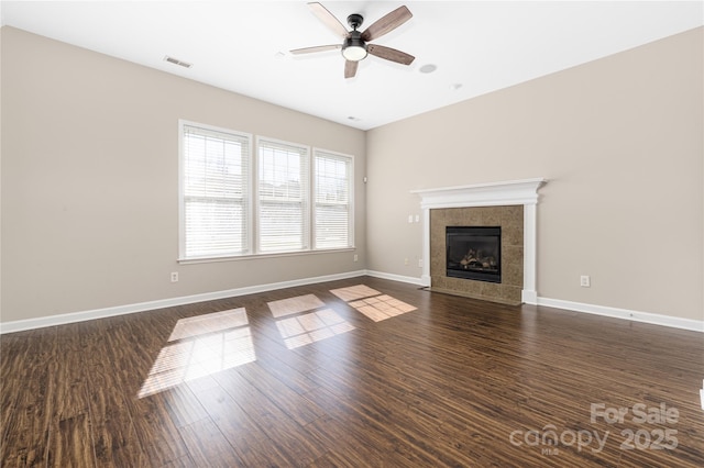 unfurnished living room featuring a fireplace, visible vents, dark wood-type flooring, ceiling fan, and baseboards